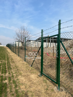 Plot z běžného pletiva s ostnatým drátem u firemního objektu