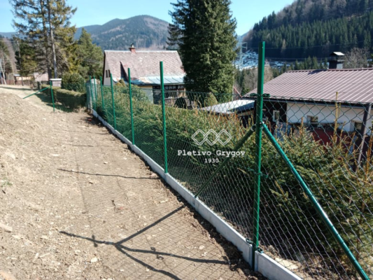 Plot z klasického pletiva s podhrabovými deskami v chatové oblasti