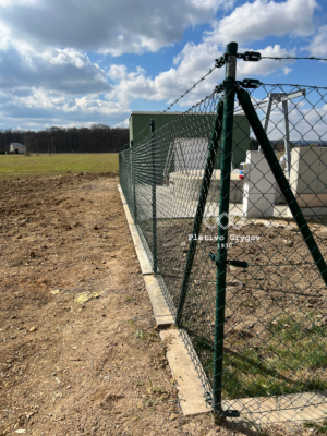 Oplocení z klasického pletiva kolem průmyslového objektu