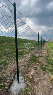 Plot z běžného pletiva s ostnatým drátem kolem firemního objektu