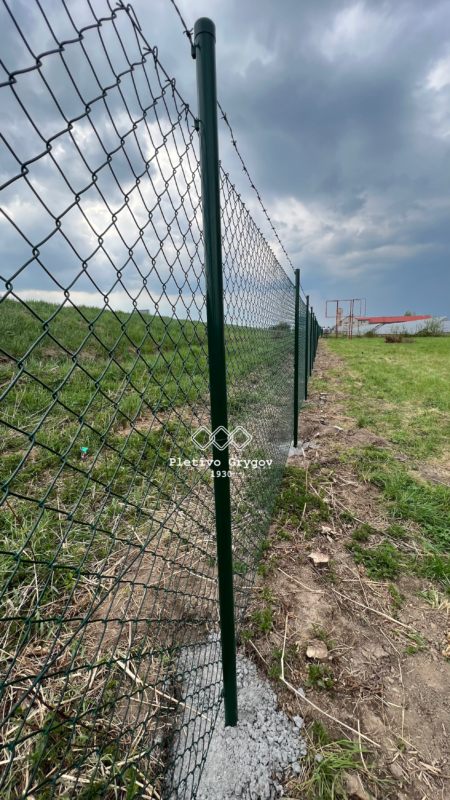 Plot z běžného pletiva s ostnatým drátem kolem firemního objektu