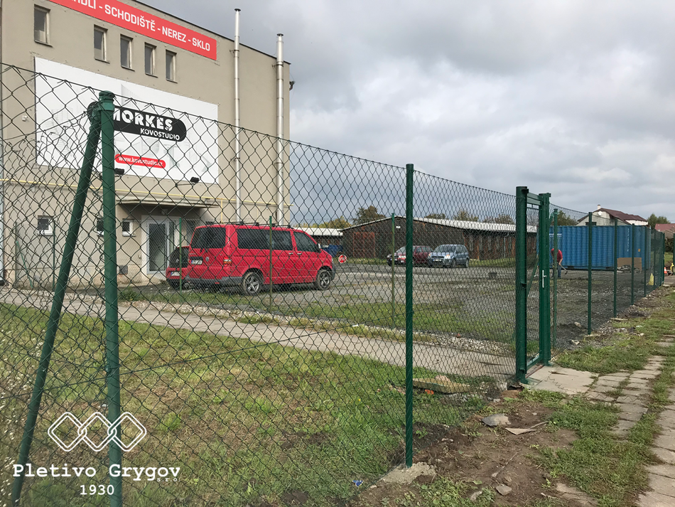 Plot z běžného pletiva kolem průmyslového objektu