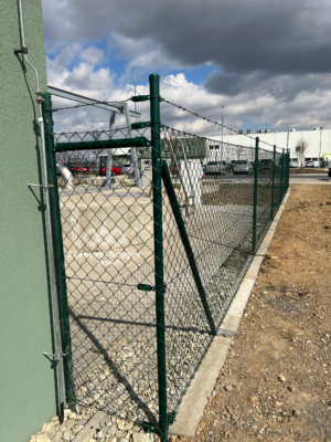 Plot z klasického s ostnatným drátem kolem firemního pozemku